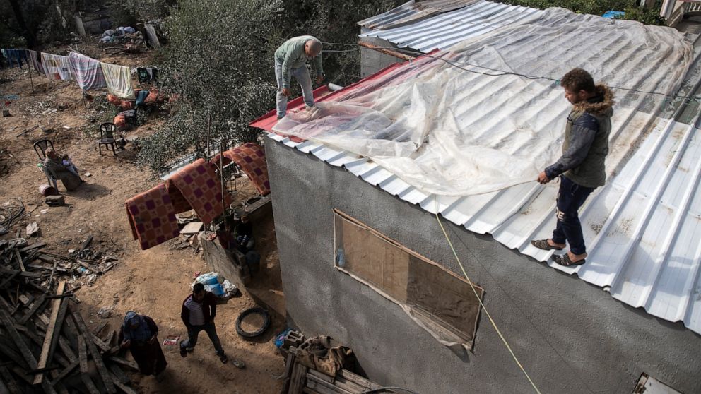 Palestinians cover the roof of their house with nylon to protect it from rain leaks after it was damaged during the 11-day Gaza war in May 2021, in the town of Beit Lahiya, northern Gaza Strip, Monday, Nov. 21, 2021. The first rainstorm of winter sen