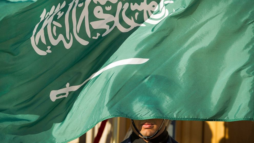 FILE - In this March 22, 2018, file photo, an honor guard member is covered by the flag of Saudi Arabia, in Washington. Saudi Arabia, for years one of the world's most prolific executioners, dramatically reduced the number of people put to death in 2