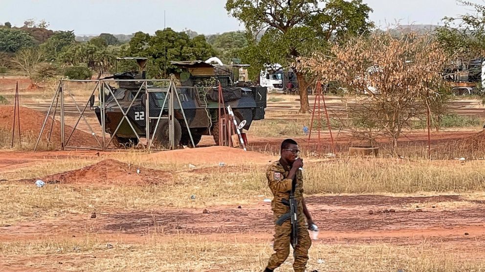 A Burkinabe soldier walks past a French Armoured Personnel Carrier part of a French military convoy heading to Niger, stopped by protesters in Kaya, Burkina Faso, Saturday Nov. 20, 2021. Residents of the city have blocked the roads to protest about t