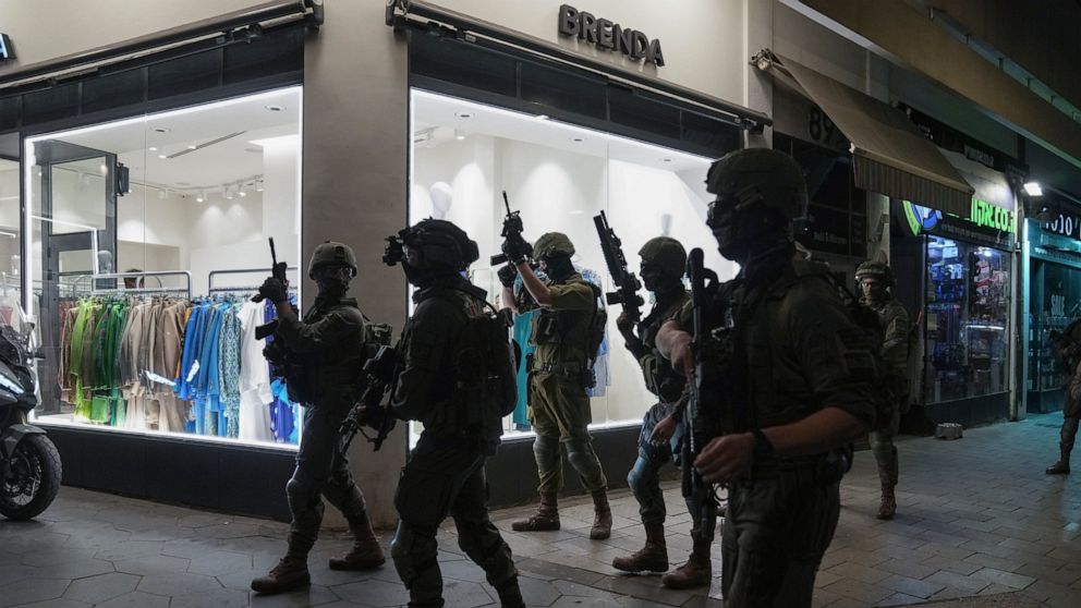 Israeli security forces search for assailants near the scene of a shooting attack in Tel Aviv, Israel, Thursday, April 7, 2022. Israeli health officials say two people were killed and at least eight others wounded in a shooting in central Tel Aviv. T