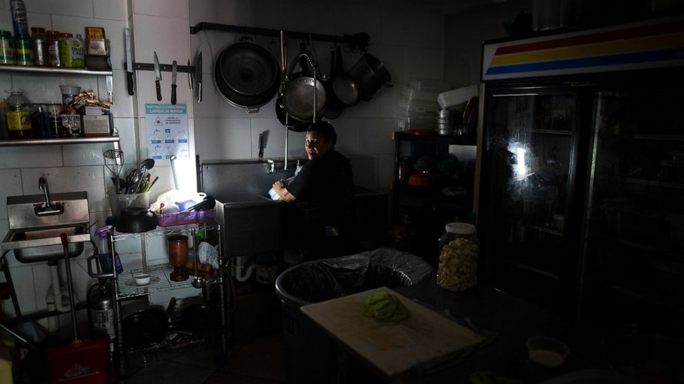 FILE - Workers at Las Palmas Cafe work with the power of an electricity generator during an island-wide blackout, in San Juan, Puerto Rico, April 7, 2022. (AP Photo/Carlos Giusti, File)