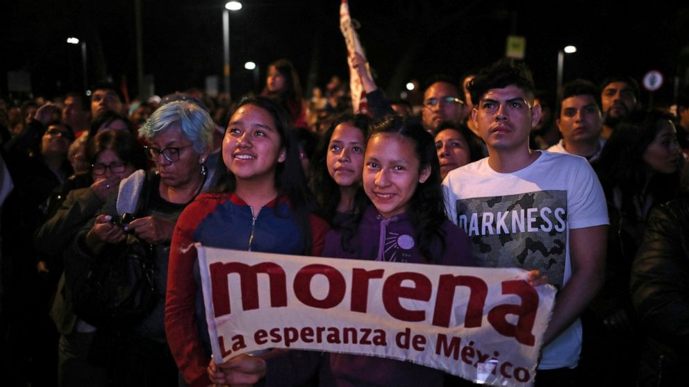 FILE - Supporters of presidential candidate Andres Manuel Lopez Obrador, of the Morena party, wait for his arrival at Mexico City's Zocalo plaza, July 1, 2018. With Morena now dominant in Mexico, the biggest question in politics has become what kind 