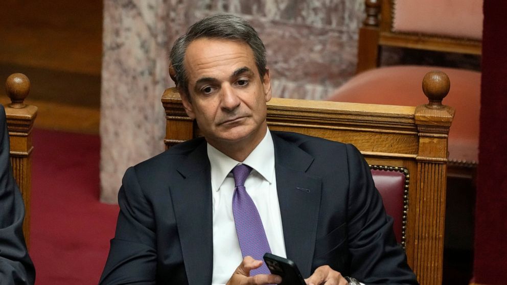 FILE - Greece's Prime Minister Kyriakos Mitsotakis holds his cellphone during a parliament session in Athens, Greece, Friday Aug. 26, 2022. Lawmakers in Greece on Thursday, Dec. 8, 2022 were debating draft legislation to outlaw commercial spyware fol