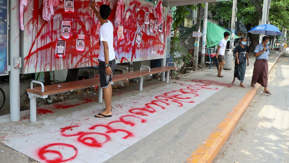 An anti-coup protester uses red paint as he writes slogans at a bus stop on Wednesday April 14, 2021 in Yangon, Myanmar. Anti-coup protesters kept public demonstrations going despite the threat of lethal violence from security forces. The words reads
