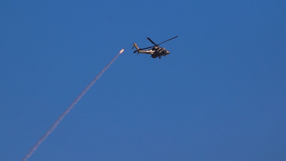 An Israeli attack helicopter flies by an Iron Dome air defense system as it launches to intercept rocket fired from Gaza Strip, at the Israeli Gaza border, southern Israel, Thursday, May 13, 2021. (AP Photo/Ariel Schalit)