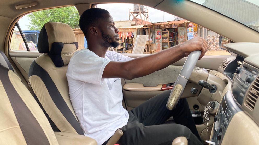 Adenekan Ayomide, 27, an undergraduate student turned a taxi driver following nationwide university strike, poses for a photograph inside his taxi in Abuja, Nigeria, Tuesday, May 10, 2022. “Nobody is talking about school again,” said Ayomide, who sai