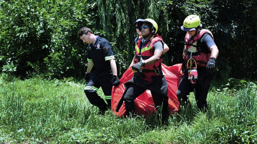 Rescuers carry the body of a flood victim that was retrieved from the Jukskei river in Johannesburg, Sunday, Dec. 4, 2022. At least nine people have died while eight others are still missing in South Africa after they were swept away by a flash flood