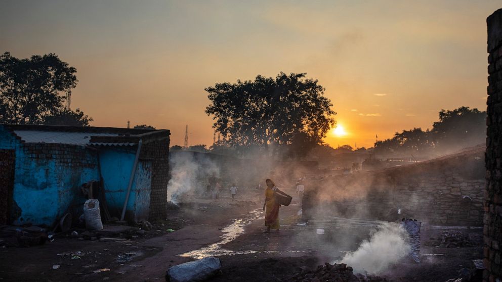 A woman walks past piles of coal burning after scavenging from an open-cast mine near Dhanbad, an eastern Indian city in Jharkhand state, Thursday, Sept. 23, 2021. On Saturday, India asked for a crucial last minute-change to the final agreement at cr