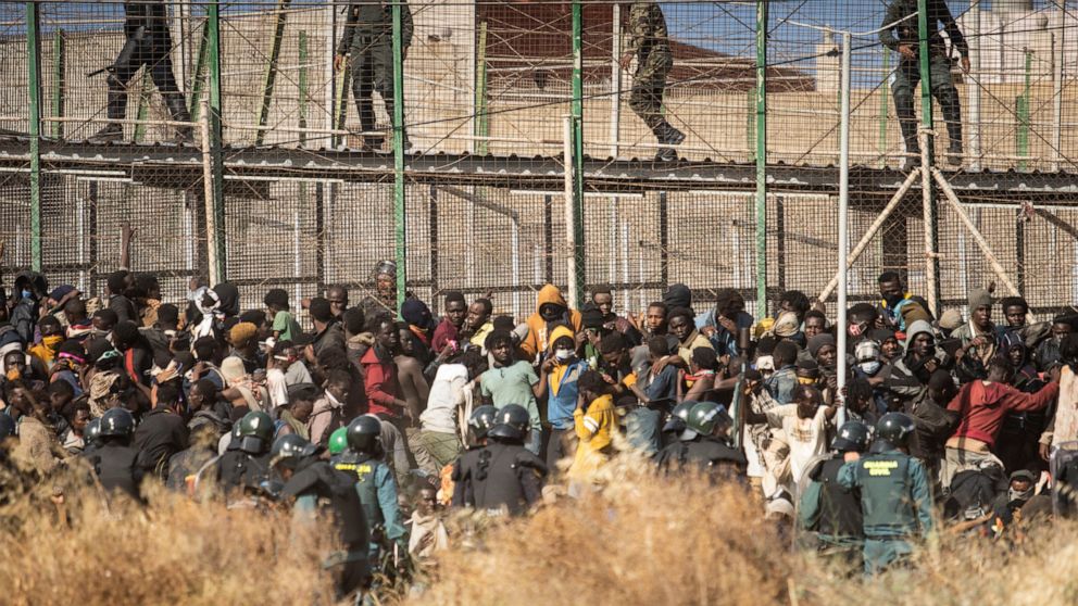 FILE - Riot police officers cordon off the area after migrants arrive on Spanish soil and crossing the fences separating the Spanish enclave of Melilla from Morocco in Melilla, Spain, Friday, June 24, 2022. Two weeks after 23 people died at the borde