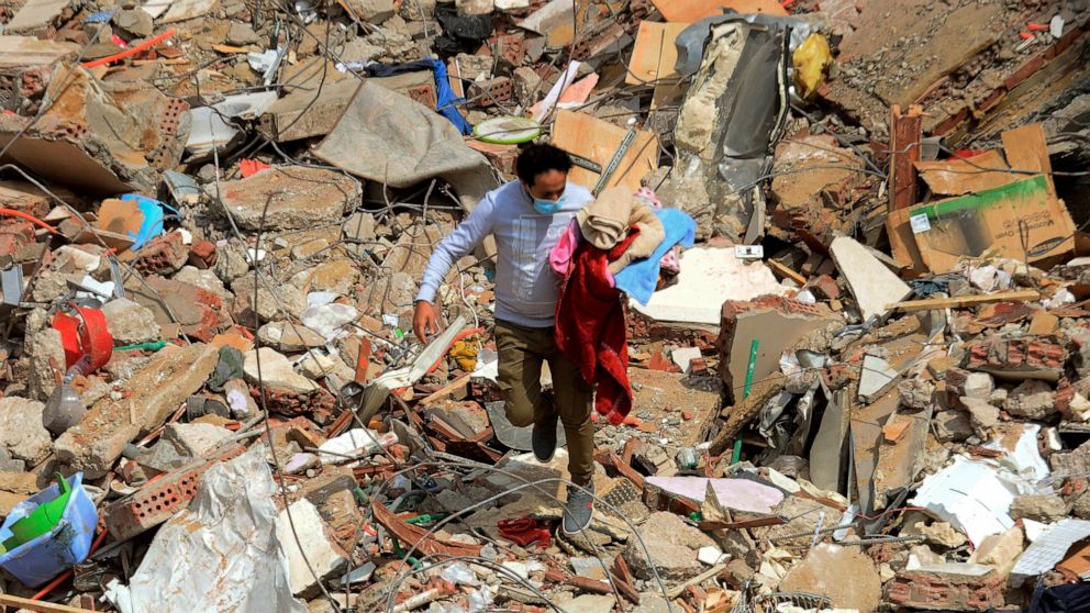 A man walks on the rubble of a collapsed apartment building in the el-Salam neighborhood, in Cairo, Egypt, Saturday, March 27, 2021. A nine-story apartment building collapsed in the Egyptian capital early Saturday, killing at several and injuring abo