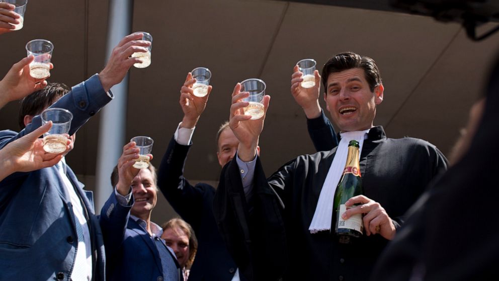 FILE - Dutch lawyer Roger Cox, right, proposes a toast on the steps of the court house in a scene setup by TV in The Hague, Netherlands, Wednesday, June 24, 2015. Roger Cox, a lawyer who helped win landmark cases forcing the Dutch government and oil 