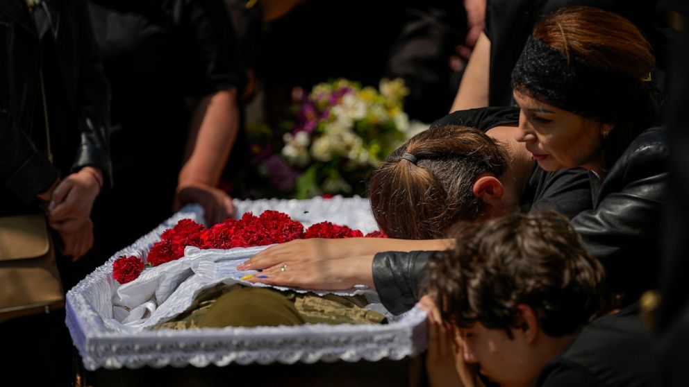 Iuliia Loseva, right, and her sons Hryhorii and Denys cry over the coffin of their husband and father Volodymyr Losev, 38, during his funeral in Zorya Truda, Odesa region, Ukraine, Monday, May 16, 2022. Volodymyr Losev, a Ukrainian volunteer soldier,