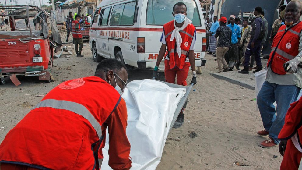 Rescue workers carry away the body of a civilian who was killed in a blast in Mogadishu, Somalia Thursday, Nov. 25, 2021. Witnesses say a large explosion has occurred in a busy part of Somalia's capital during the morning rush hour. (AP Photo/Farah A