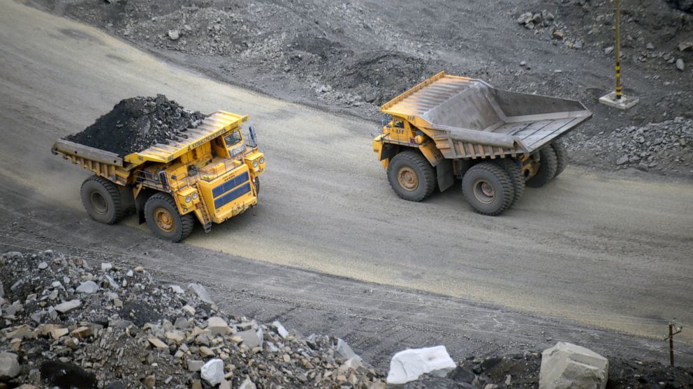 FILE - A loaded dump truck passes an empty truck as it carries away coal at the Kedrovsky open-pit coal mine in Kemerovo, Russia, Tuesday, June 16, 2015. Poland’s government has decided to block imports of coal from Russia. The move is an element in 