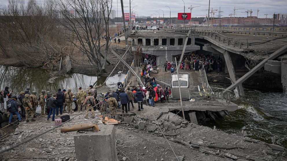 People cross on an improvised path under a bridge that was destroyed by a Russian airstrike, while fleeing the town of Irpin, Ukraine, Saturday, March 5, 2022. What looked like a breakthrough cease-fire to evacuate residents from two cities in Ukrain