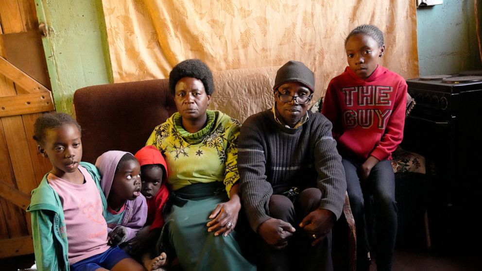 Jeffrey Carlos,centre,poses for a photo with some of his family members on the outskirts of Harare on Wednesday, Aug, 3, 2022. Carlos, a father of three, says he gets about $100 dollars a month from his job as an overnight security guard for a church