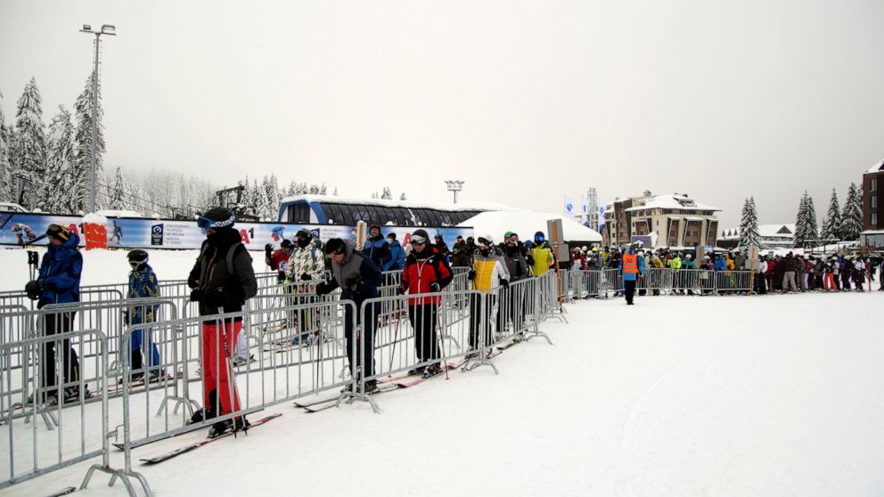 Skiers wait in a lift queue on Mount Kopaonik, Serbia, Thursday, Dec. 9, 2021. As most of Europe reintroduces measures to help curb the spread of the omicron variant, Bosnia, to the delight of its winter tourism industry, still maintains a relatively