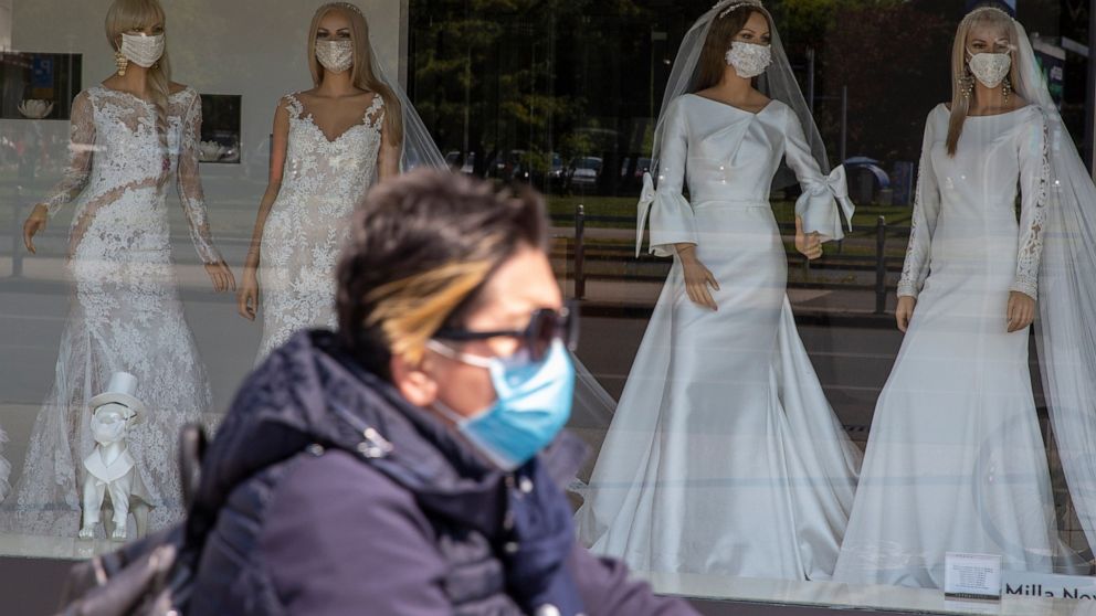 A cyclist wearing a protective mask to protect against coronavirus rides past a wedding dress store with mannequins wearing face masks, in Zagreb, Croatia, Thursday, April 23, 2020. The store is closed because of Covid-19 lockdown. (AP Photo/Darko Bandic)