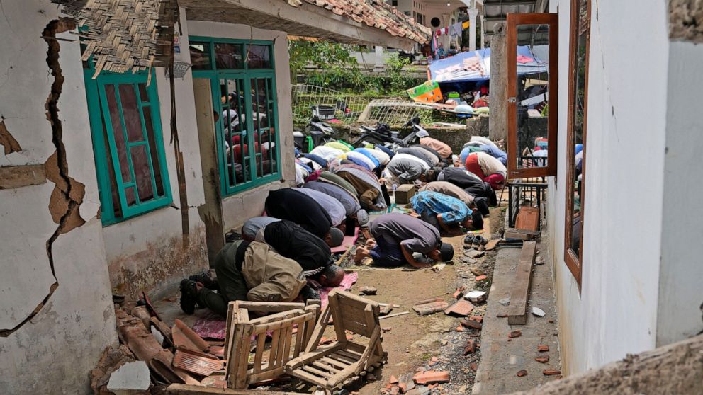 Muslim men perform a Friday prayer outside a mosque badly damaged in Monday's earthquake, in Gasol village, Cianjur, West Java, Indonesia, Friday, Nov. 25, 2022. The quake on Monday killed hundreds of people, many of them children and injured thousan