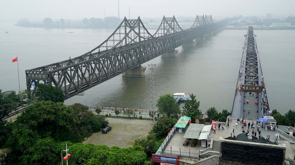 FILE - Visitors walk across the Yalu River Broken Bridge, right, next to the Friendship Bridge connecting China and North Korea in Dandong in northeastern China's Liaoning province, Sept. 9, 2017. After spending two years in a strict lockdown because