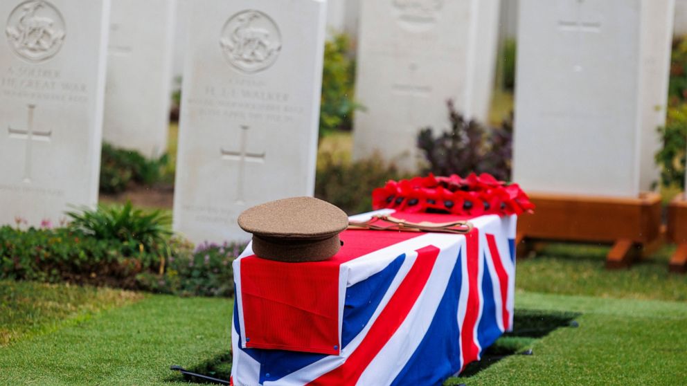 A regimental hat and a poppy wreath are placed on the coffin of an unidentified British World War I soldier during a burial ceremony with full military honors at the Irish Farm Commonwealth War Graves Cemetery in Ypres, Belgium, on Thursday June 30, 