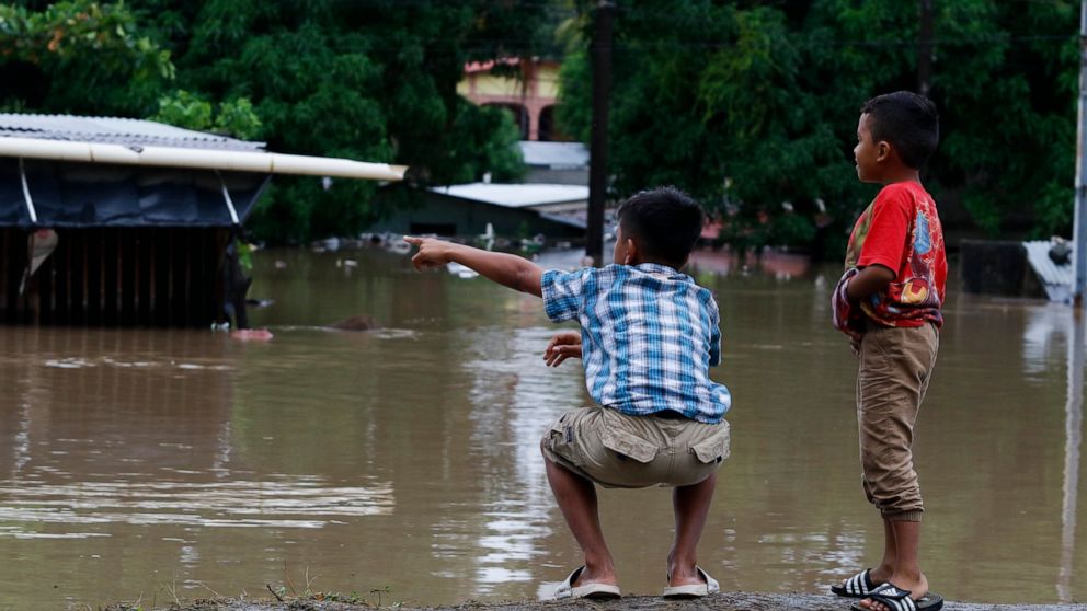 Children look at a flooded residential area near a river after the passing of Iota in La Lima, Honduras, Wednesday, Nov. 18, 2020. Iota flooded stretches of Honduras still underwater from Hurricane Eta, after it hit Nicaragua Monday evening as a Cate