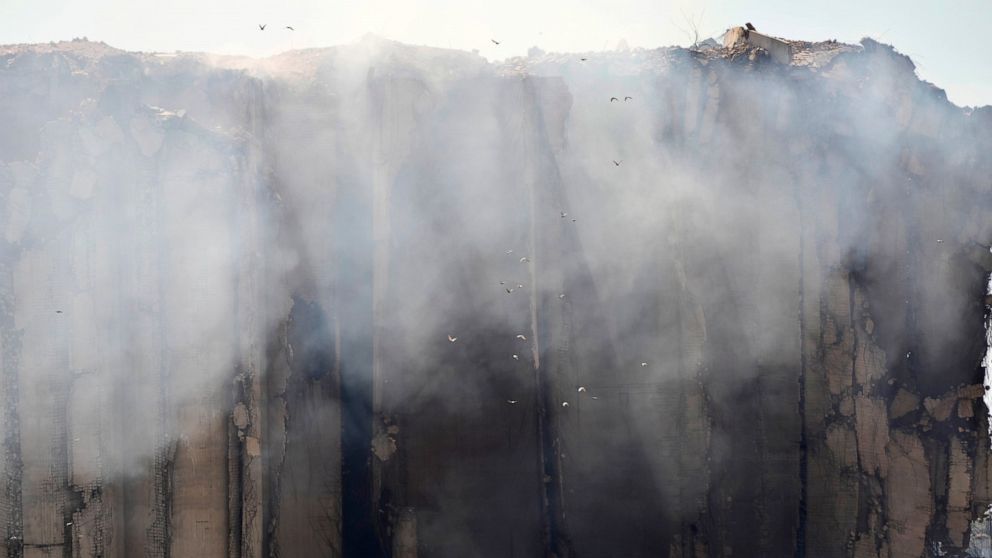 Birds fly as smoke rises from the silos in the north block of Beirut Port, Monday, July 25, 2022, in Beirut, Lebanon, after they caught fire. The silos were destroyed by a massive explosion in 2020. Lebanon's Environment and Health Ministries warned 