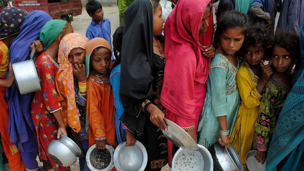 People from flood-affected areas wait to receive food distributed by the Saylani Welfare Trust, in Lal Bagh, Sindh province, Pakistan, Tuesday, Sept. 13, 2022. The death toll from three months of record-breaking floods in Pakistan rose to over 1,400,