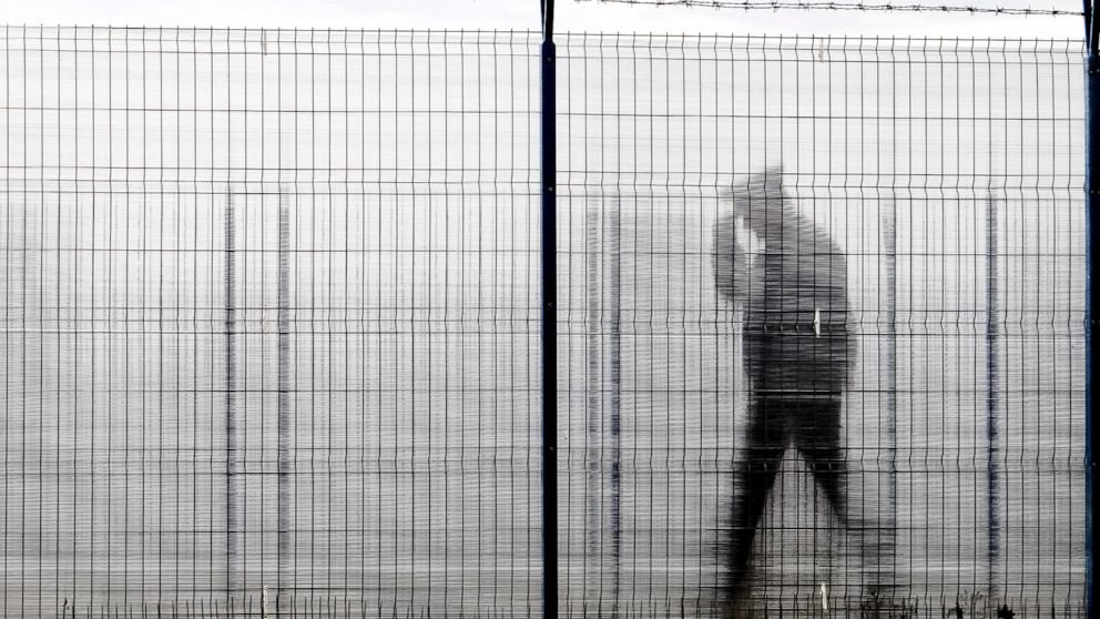 FILE - A Romanian border police officer, seen through a plexiglass fence, patrols a railway border crossing point between Romania and Moldova in Ungheni, Romania, on Jan. 18, 2011. European Union countries will weigh on Thursday, Dec. 8, 2022, whethe
