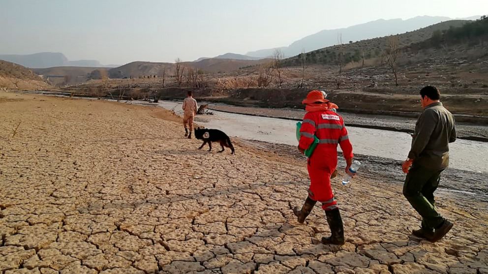 In this photo provided by the Iranian Red Crescent Society on Saturday, July 23, 2022, members of a rescue team search for missing people of Friday's flash floods in Iran's drought-stricken southern Fars province, Iran. Heavy rains swelled the Roudba