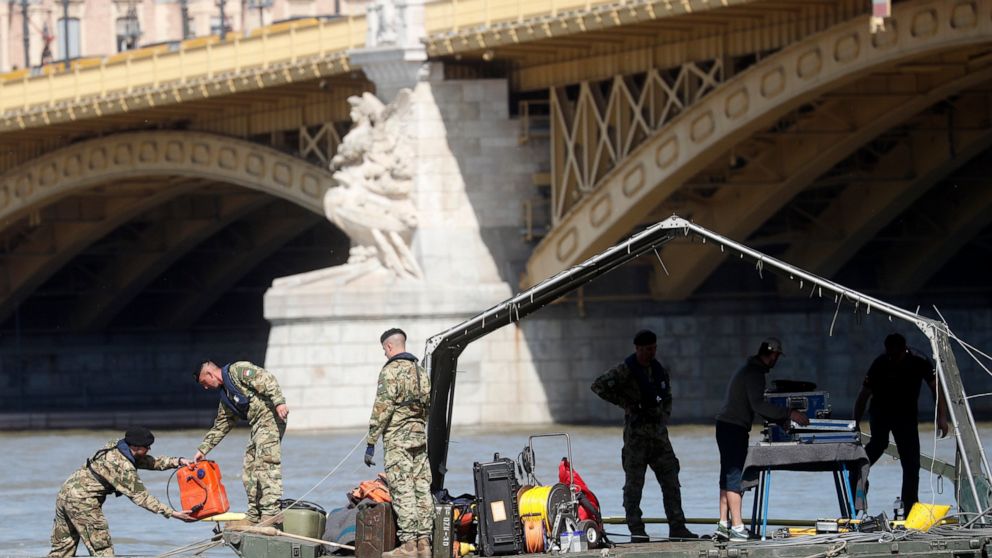Rescue team members are seen on a barge floating on the Danube river where a sightseeing boat capsized in Budapest, Hungary, Saturday, June 1, 2019. As divers descended Friday into the Danube, Hungarian authorities predicted it would take an extended