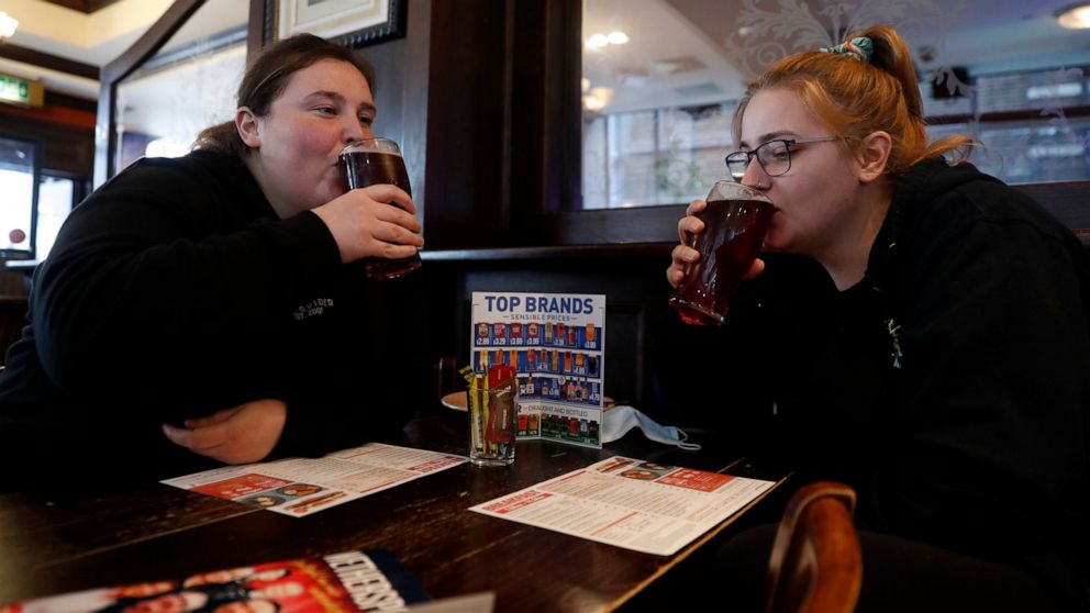 Libby Jones, right, with her colleague Shannon Maiden, both nurses from Great Ormond Street hospital who have just finished an overnight shift, have a pint of cider at the Shakespeare's Head pub, which will be reopening for the first time to serve in