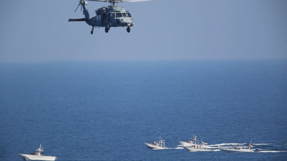 FILE - In this Dec. 21, 2018 file photo, a U.S. MH-60 Seahawk helicopter flies over Iranian Revolutionary Guard patrol boats in the Strait of Hormuz. The top U.S. Navy official in the Mideast, said Sunday, Dec. 6, 2020, that America has reached an "u