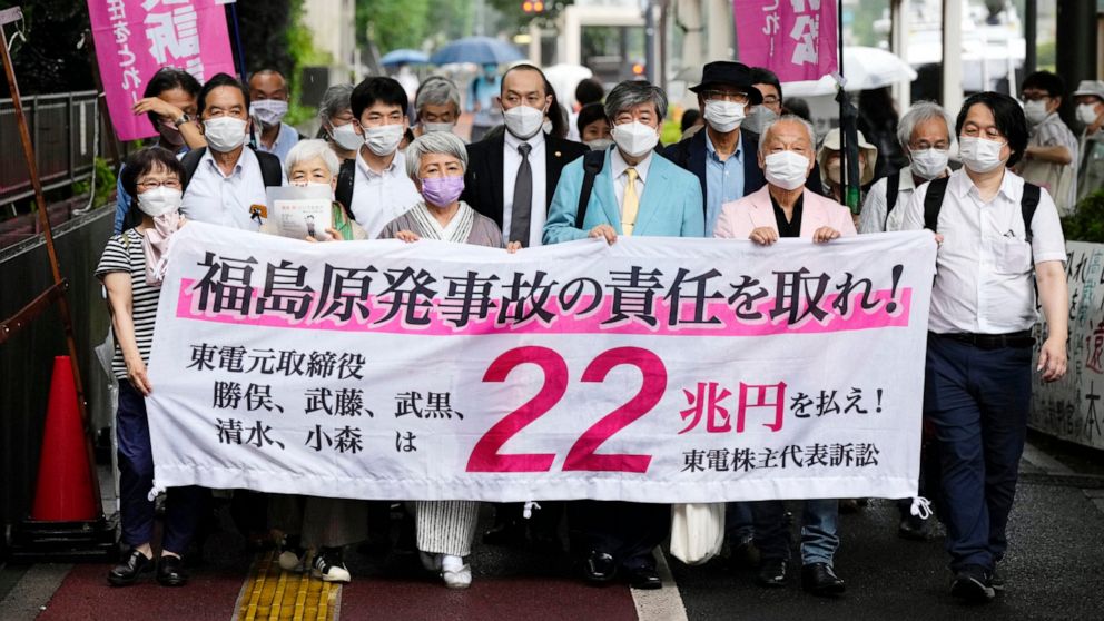 A group of TEPCO shareholders who filed a suit in 2012 demanding that former executives pay billions of money in damages to the company walk to the Tokyo District Court in Tokyo, Wednesday, July 13, 2022. The Tokyo court on Wednesday ordered four for