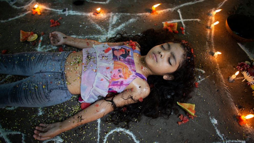 A girl lies surrounded by candles and designs of white powder during a ceremony on Sorte Mountain, Sunday, Oct. 13, 2019, where followers of indigenous goddess Maria Lionza gather annually in Venezuela's Yaracuy state. Believers congregated for ritua