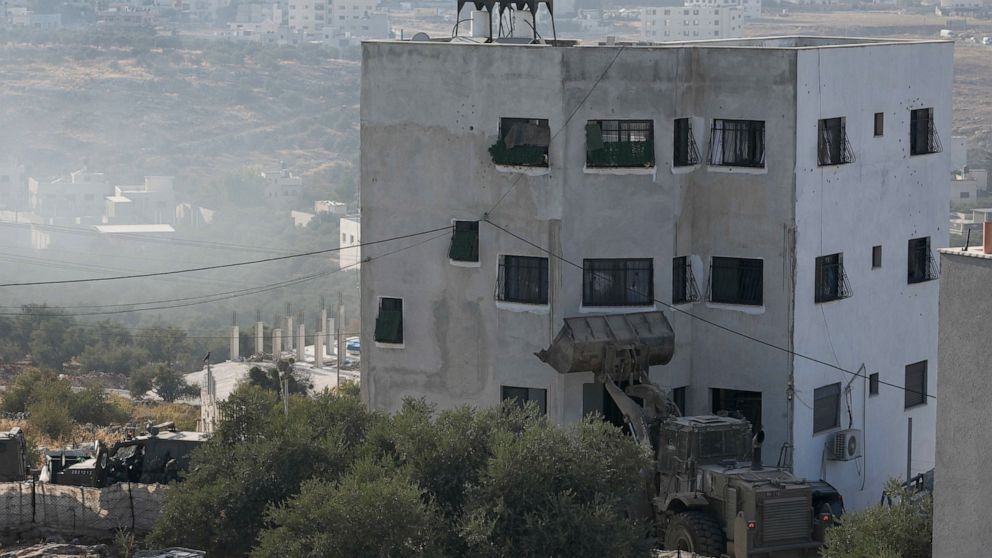 Israeli soldiers surround a Palestinian house during a raid in the village of Deir al-Hatab, near the West Bank city of Nablus, Wednesday, Oct. 5, 2022. The Palestinian Health Ministry says a Palestinian man has been killed by Israeli army fire as tr