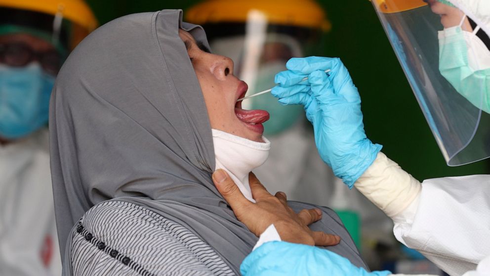 Health workers collect nasal swab samples from a woman during a mass test for the new coronavirus at a market in Jakarta, Indonesia, Thursday, June 25, 2020. (AP Photo/Tatan Syuflana)
