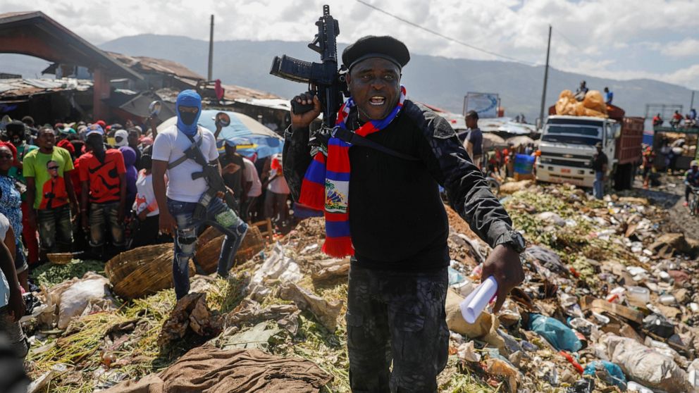 FILE - Barbecue, the leader of the "G9 and Family" gang, stands next to garbage to call attention to the conditions people live in as he leads a march against kidnapping through La Saline neighborhood in Port-au-Prince, Haiti, Friday, Oct. 22, 2021. 
