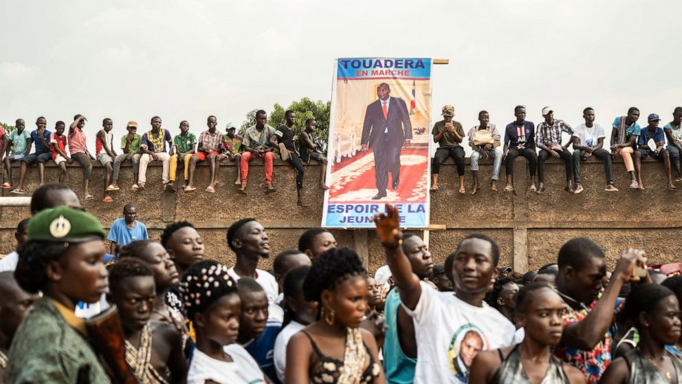 In this photo released by Xinhua News Agency, supporters gather near the poster of Faustin-Archange Touadera, President of the Central African Republic, as they take part in a campaign rally in Bangui, Central African Republic, Dec. 12, 2020. China e