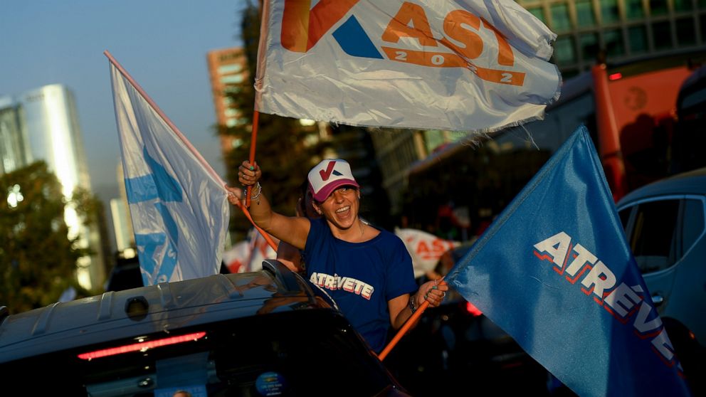 A follower of Chile's presidential candidate Jose Antonio Kast from the Partido Republicano, holds campaign flags during a rally in Santiago, Chile, Wednesday, Dec. 15, 2021. Chile votes in the runoff election on Dec. 19. (AP PhotoMatias Delacroix)