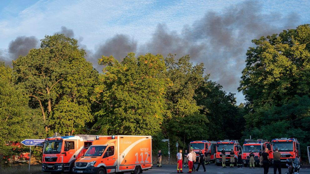Fire engines and ambulances stand on Kronprinzessinnen road at the Grunewald forest in Berlin, Germany, Thursday, Aug. 4, 2022. A large fire has broke out in one of Berlin’s biggest forests triggered by several explosions that took place on a blastin