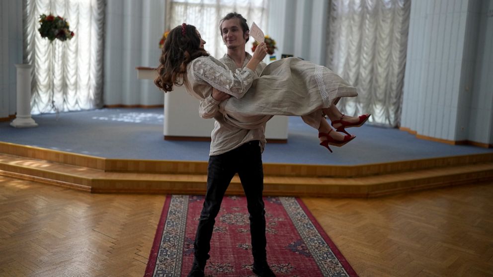 Yevhen Nalyvaiko holds Daria Ponomarenko minutes after getting married in Kyiv, Ukraine, Wednesday, June 15, 2022. A growing number of couples in Ukraine are speedily turning love into matrimony because of the war with Russia. Some are soldiers, marr