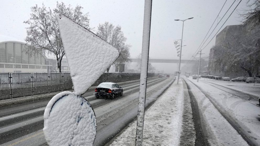 Cars on the street during snow storm in Belgrade, Serbia, Sunday, Dec. 12, 2021. Meteorologists predict heavy snowfall and sub zero temperatures in the Western Balkans throughout the week. (AP Photo/Darko Vojinovic)