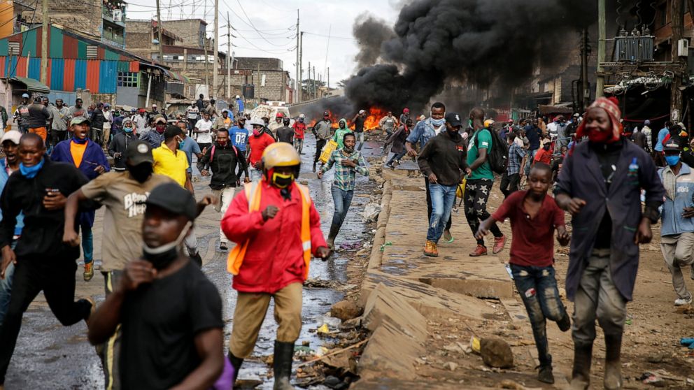 Residents and protesters flee during clashes with police next to burning tyre barricades in the Kariobangi slum of Nairobi, Kenya Friday, May 8, 2020. Hundreds of protesters blocked one of the capital's major highways with burning tires to protest go