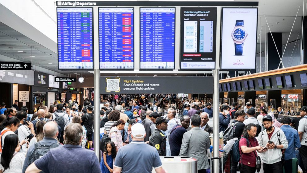 Passengers wait in front of a display board at Zurich airport, in Zurich, Wednesday, June 15, 2022. Switzerland’s air traffic controller says Swiss airspace has been reopened after a brief closure for safety reasons due to an unspecified “technical m