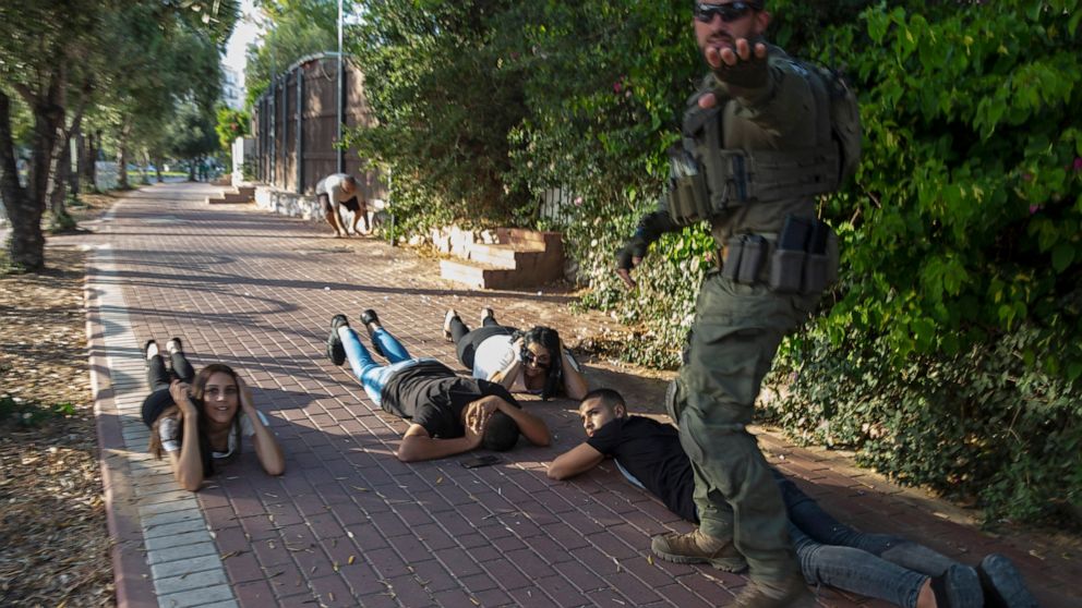 Israelis take cover as a siren sounds a warning of incoming rockets fired from the Gaza Strip, in Ashkelon, southern Israel, Sunday, May 16, 2021. (AP Photo/Heidi Levine)