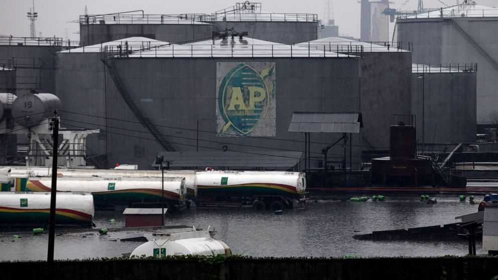 FILE- A tank farm and oil trucks are half submerged after a downpour at an oil terminal in Lagos Nigeria, on July. 11, 2011. Nigerian state gas company has declared a force majeure after floods hindered gas operations, raising concerns among analysts