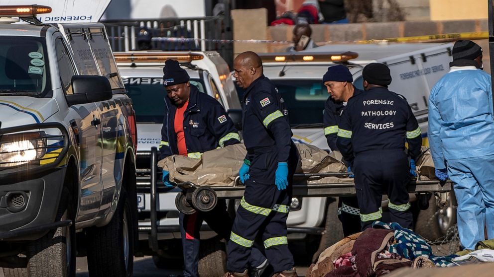 A body is removed from the scene of an overnight bar shooting in Soweto, South Africa, Sunday July 10, 2022. A mass shooting at a tavern in Johannesburg's Soweto township has killed 15 people and left others in critical condition, according to police