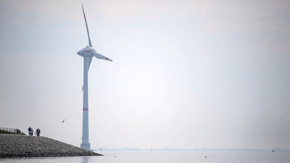 Cyclists ride along the dyke in Emden, Germany, Wednesday, June 3, 2020. The German government wants to increase offshore wind power capacity five-fold by 2040 as part of its plan to wean the country off fossil fuels. Cabinet on Wednesday agreed a bi