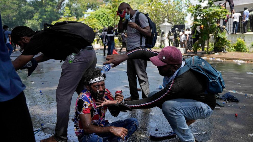 A protester helps another after police fired teargas to disperse them before they stormed Sri Lankan Prime Minister Ranil Wickremesinghe's office, demanding he resign after president Gotabaya Rajapaksa fled the country amid economic crisis in Colombo